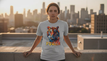 A person in a grey t-shirt with a tiger graphic stands calmly on a sunlit city rooftop.