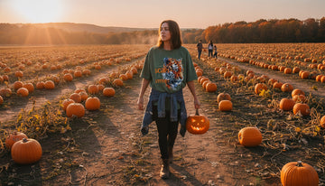 A person in a moss-colored tiger tee walks through a pumpkin patch at sunset, carrying a carved pumpkin and a denim jacket.