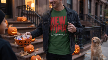 Person wearing a white t-shirt while handing out candy on a decorated porch at dusk.