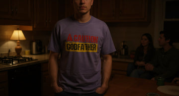 A calm person in a graphic tee stands at a kitchen counter at dusk while family gathers around a long table in lamp light.